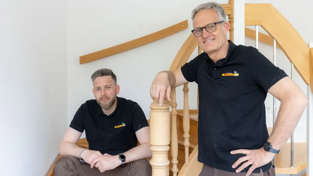 Markus Kaymer sitzt links auf einer Treppe. Rechts neben der Treppe steht Klaus Herold.